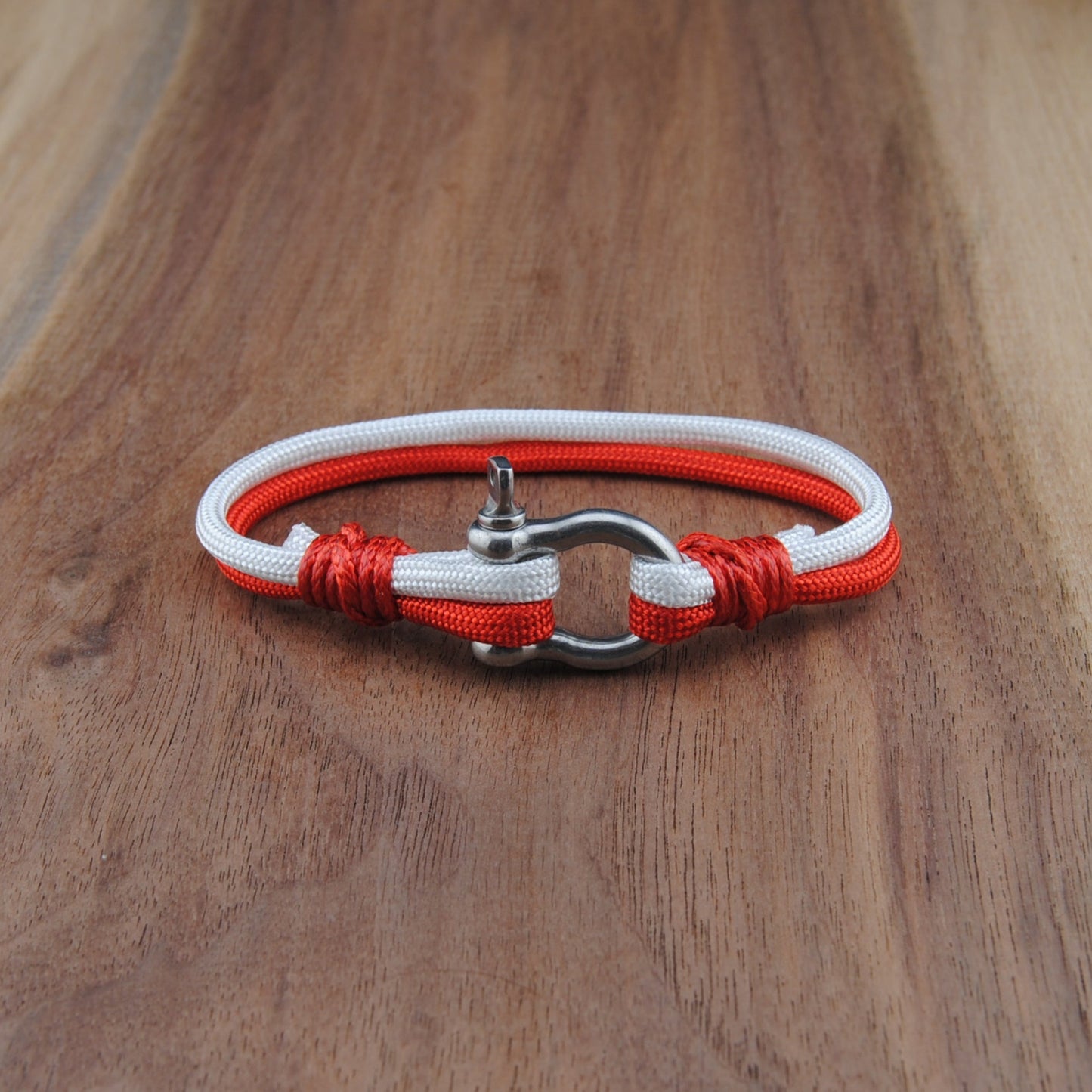 Bracelet with red and white cord on a wooden surface