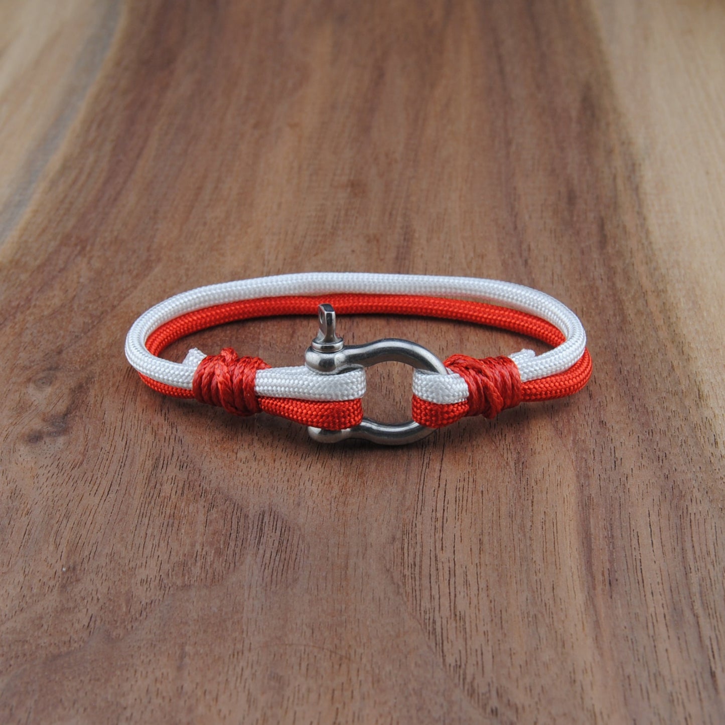 Bracelet with red and white cord on a wooden surface