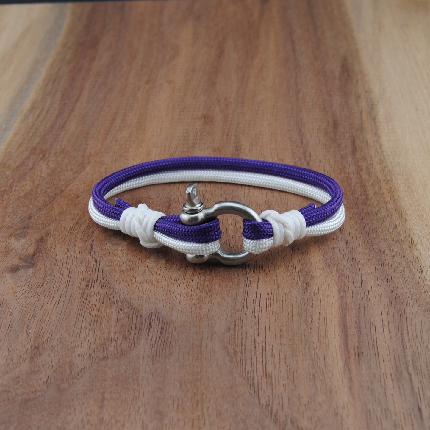 Bracelet with purple and white cord on a wooden surface