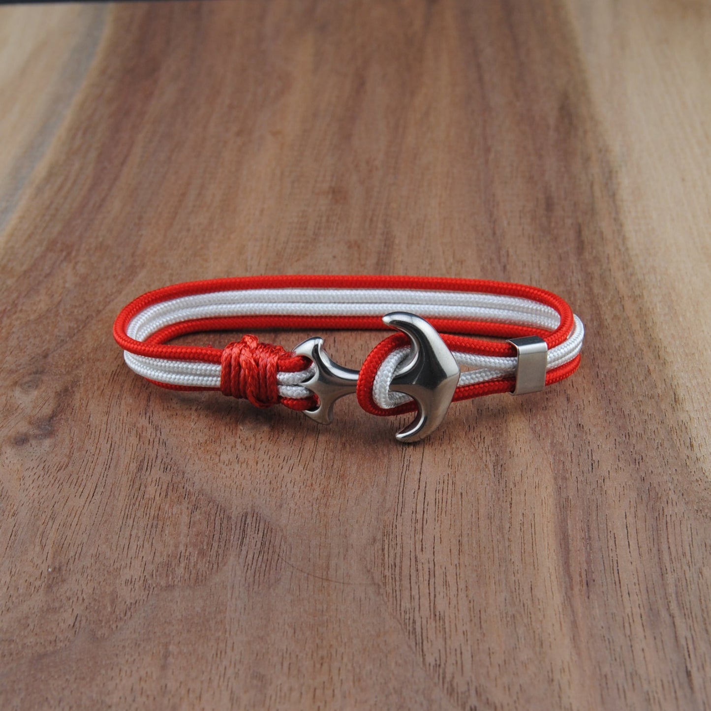 Bracelet with red and white cord and silver clasp on a wooden surface