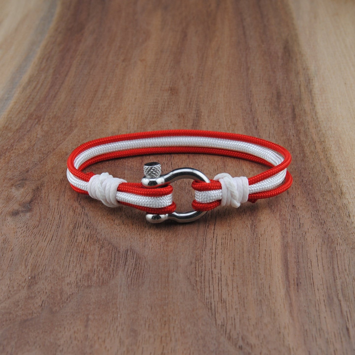 Red and white bracelet with metal clasp on a wooden surface