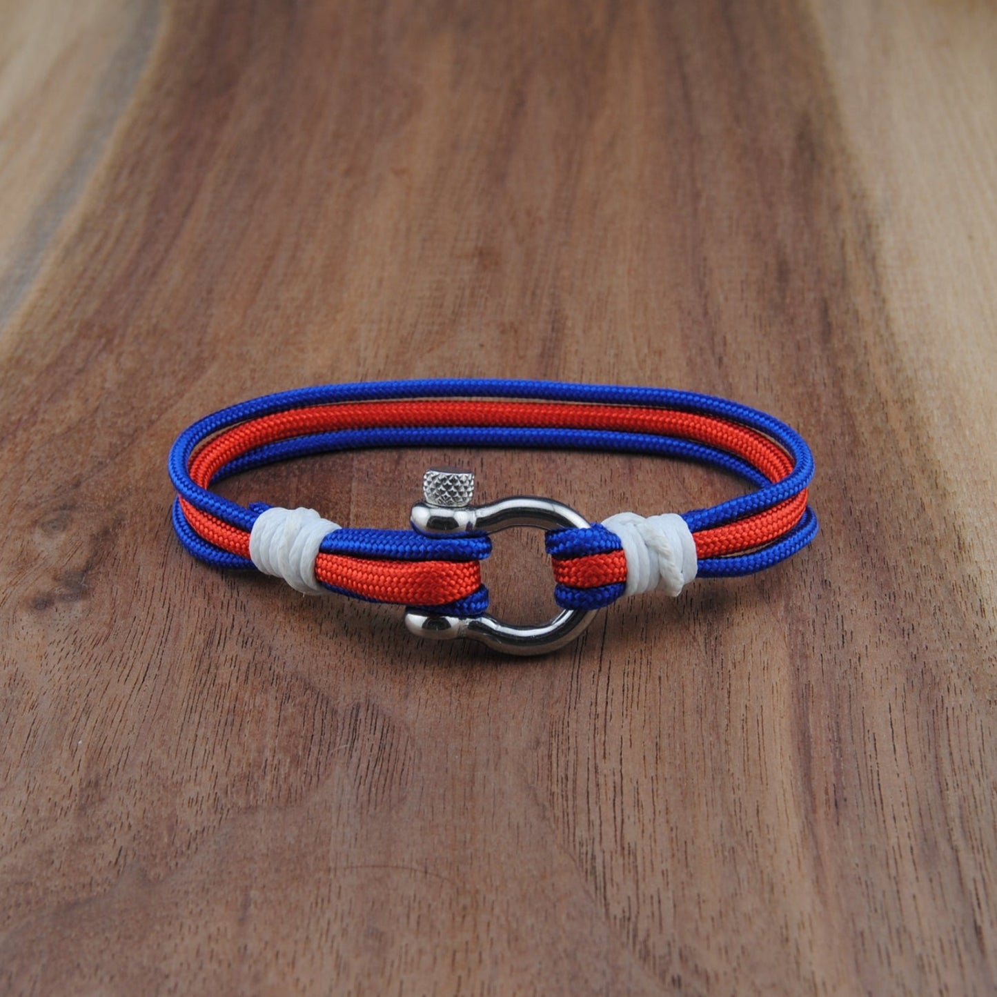 Bracelet with red, blue, and white straps on a wooden surface
