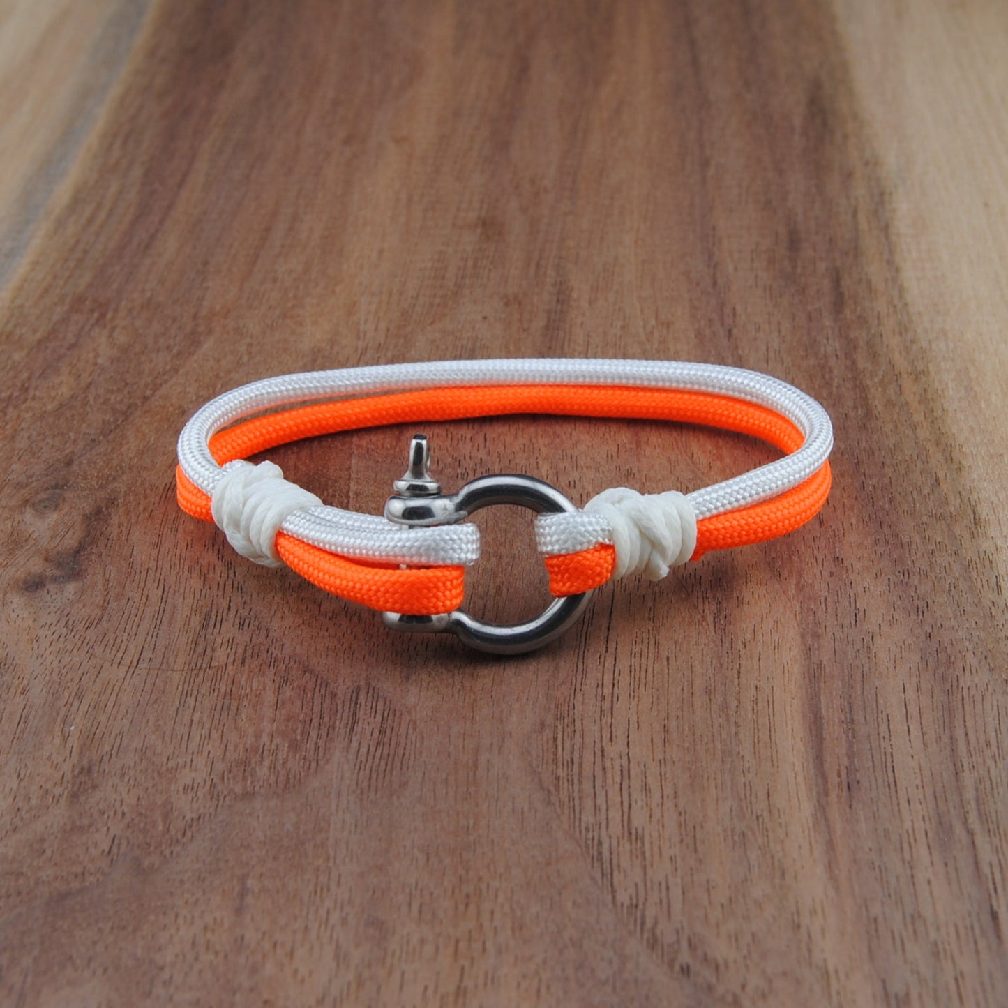 Neon orange and white bracelet on a wooden surface