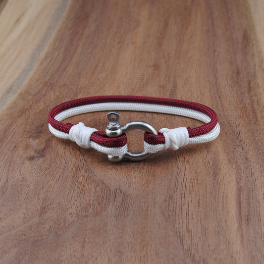 Bracelet with red and white cord and metal clasp on a wooden surface
