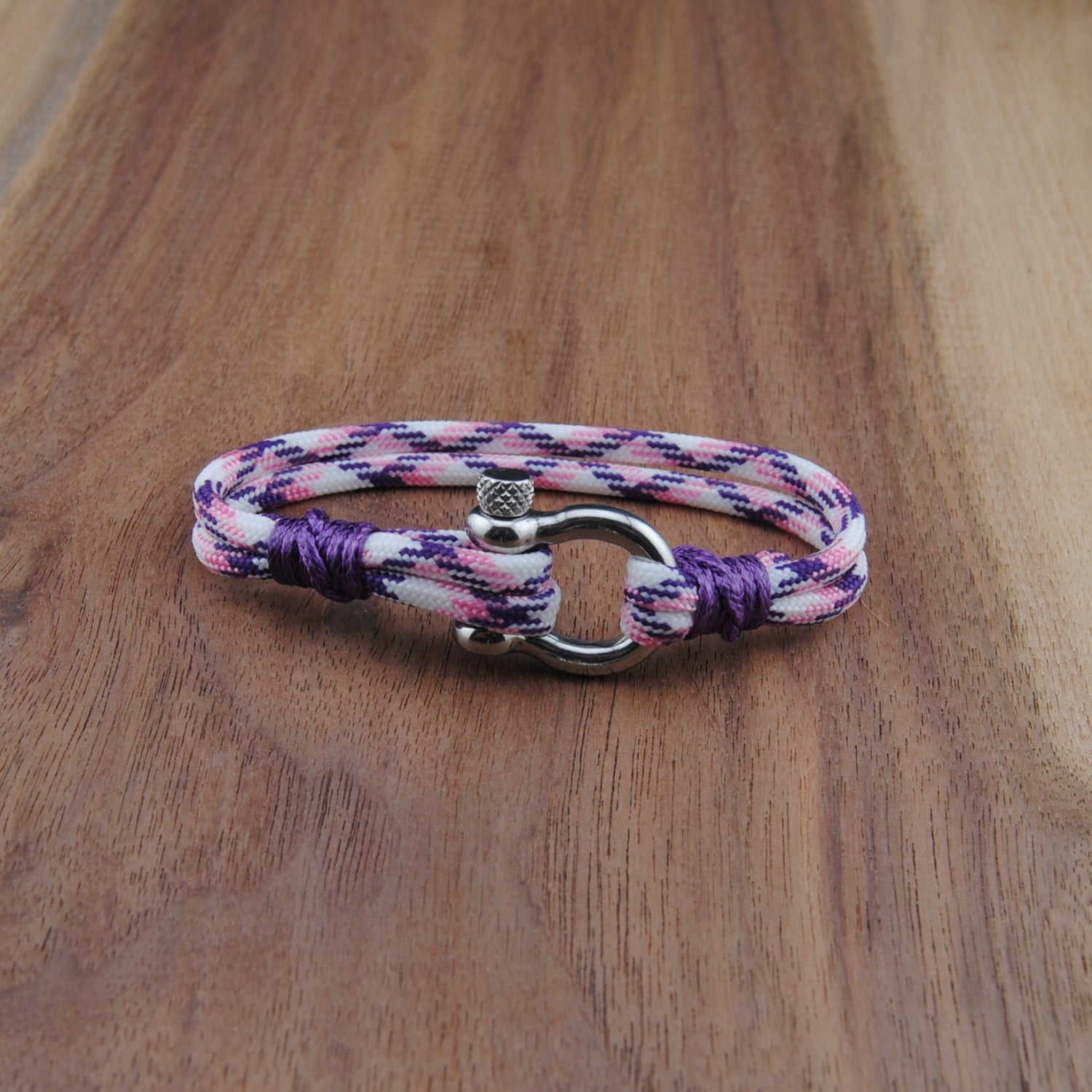 Multicolored braided bracelet with a clasp on a wooden surface