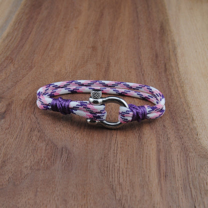 Multicolored braided bracelet with a clasp on a wooden surface