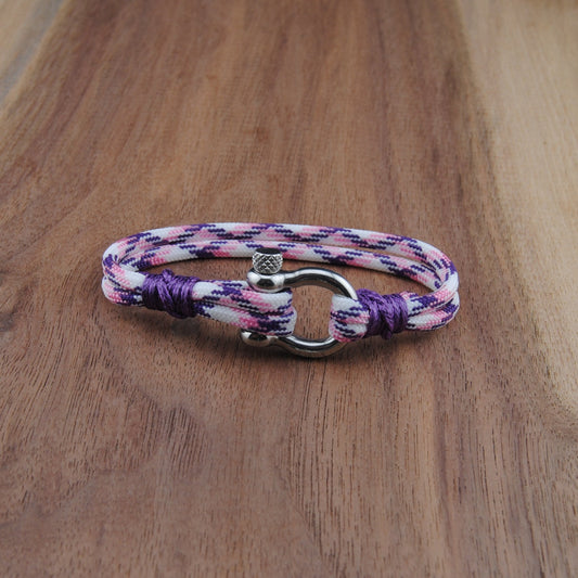 Multicolored braided bracelet with a clasp on a wooden surface