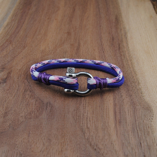 Purple braided bracelet with a silver clasp on a wooden surface