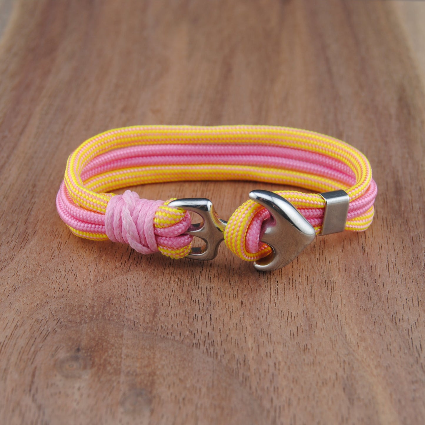 Pink and yellow bracelet with a silver clasp on a wooden surface