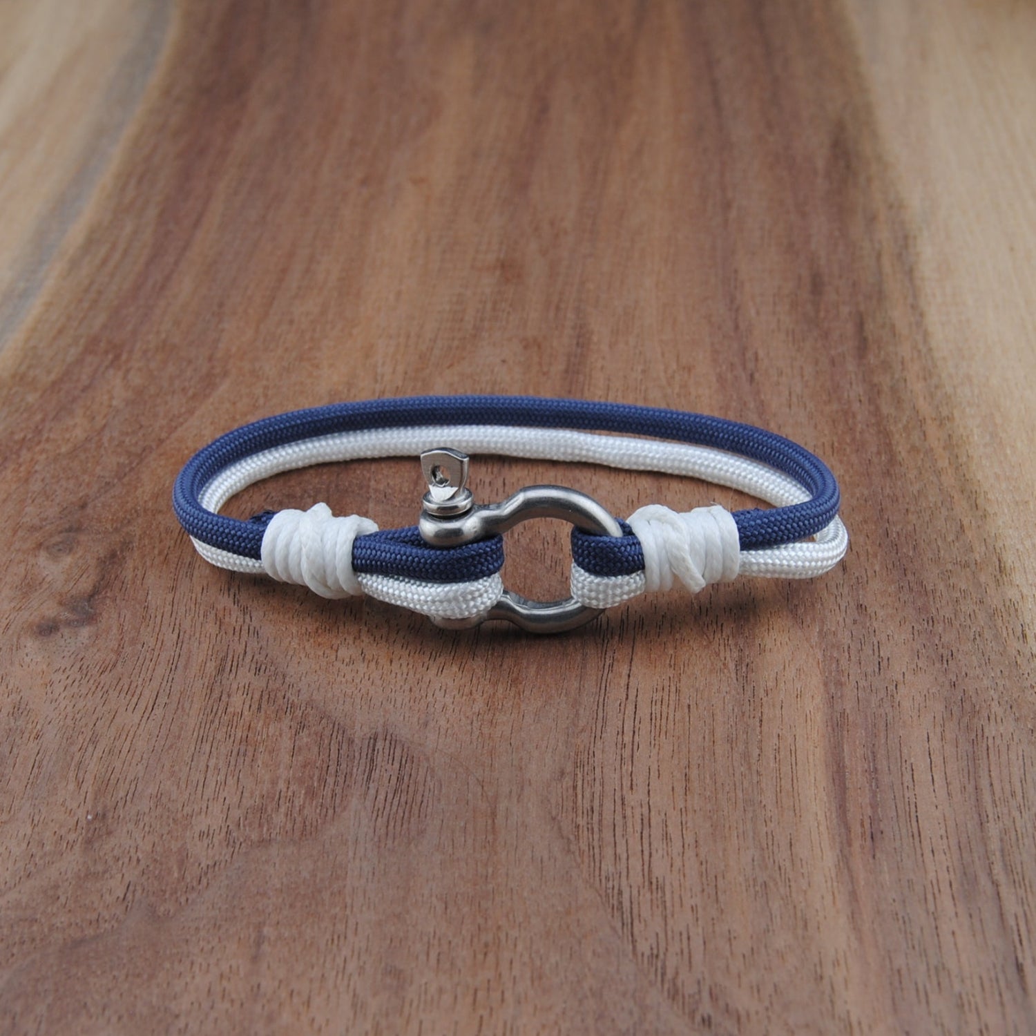 Nautical-style bracelet with blue and white cord on a wooden surface