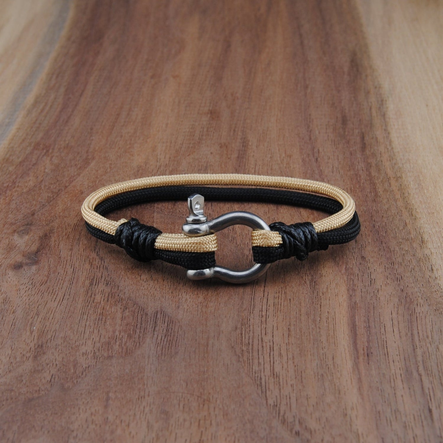 Bracelet with black and beige cord on a wooden surface