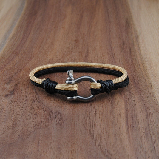 Bracelet with black and beige cord on a wooden surface