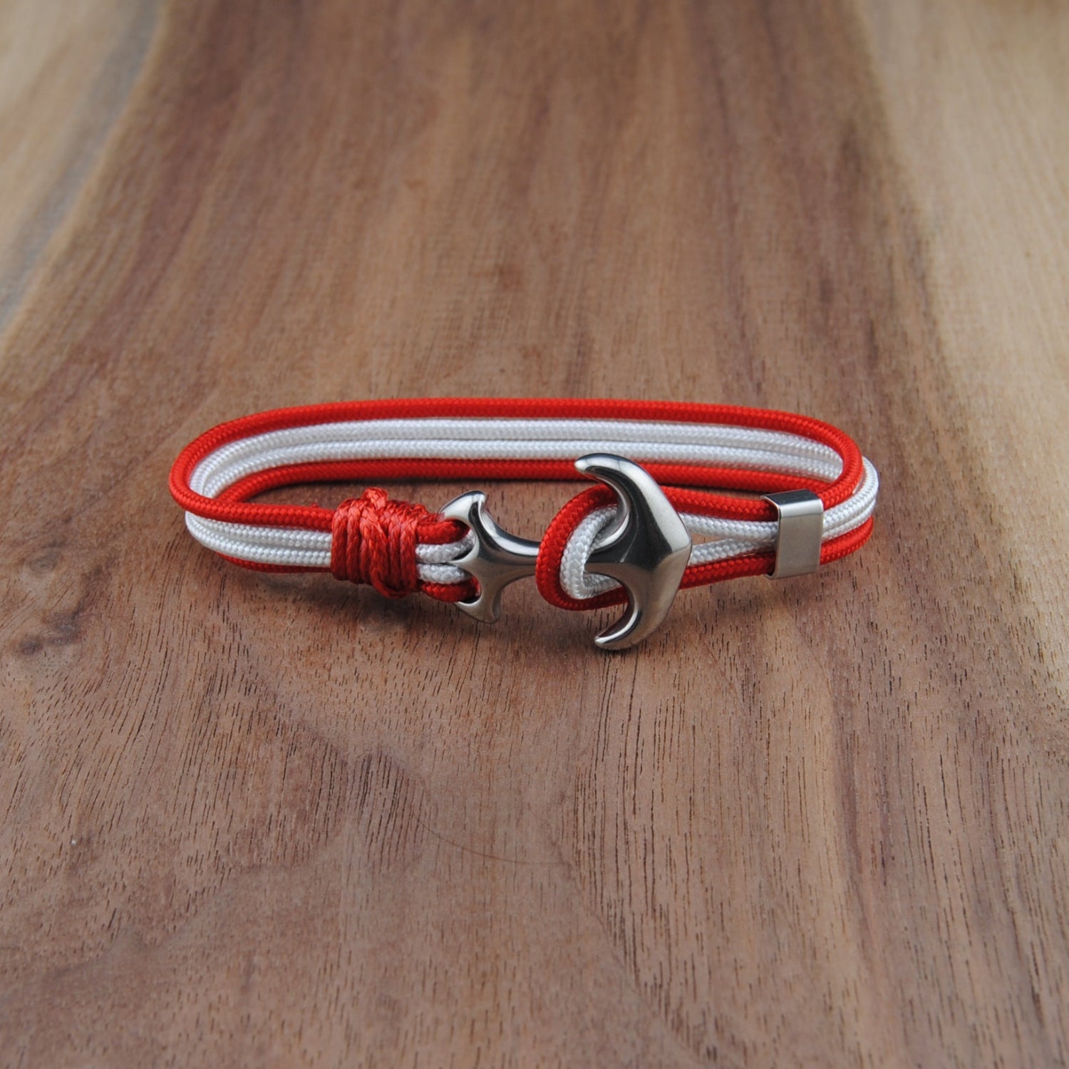 Bracelet with red and white cord and silver clasp on a wooden surface