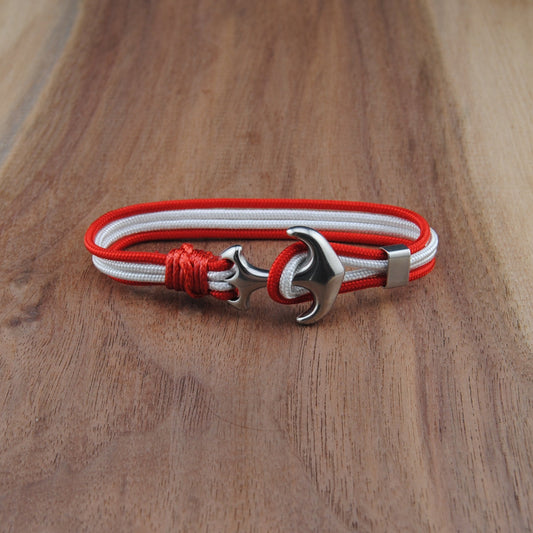 Bracelet with red and white cord and silver clasp on a wooden surface