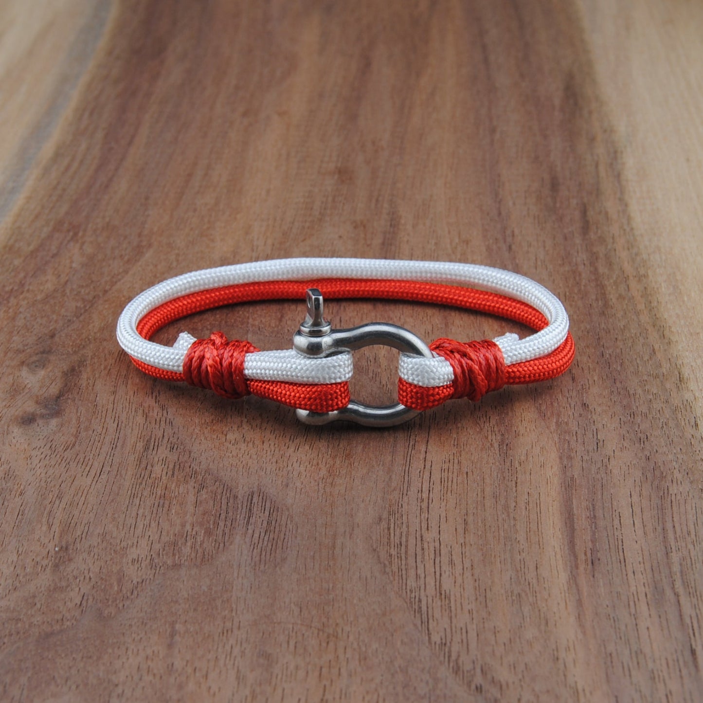 Bracelet with red and white cord on a wooden surface