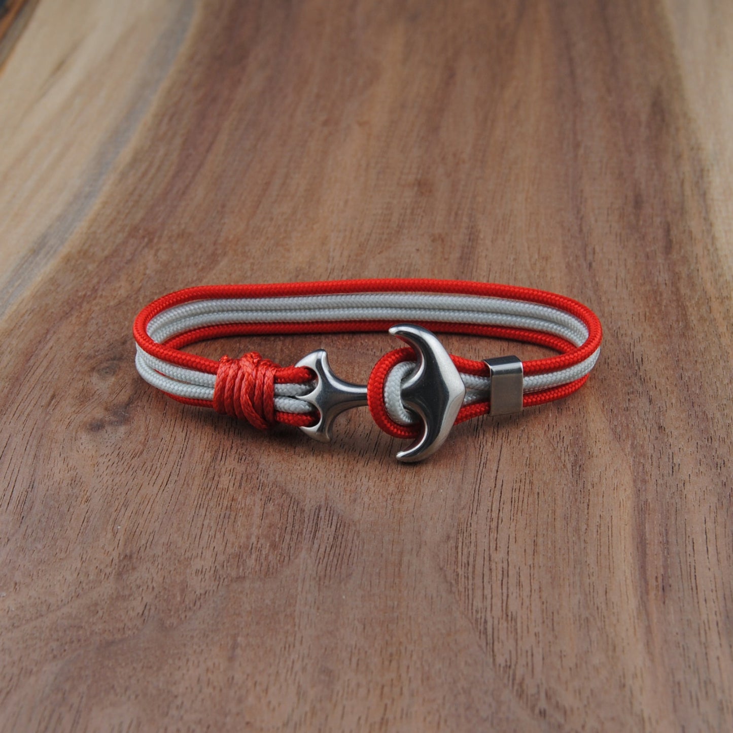 Bracelet with red and white straps and metal clasp on a wooden surface