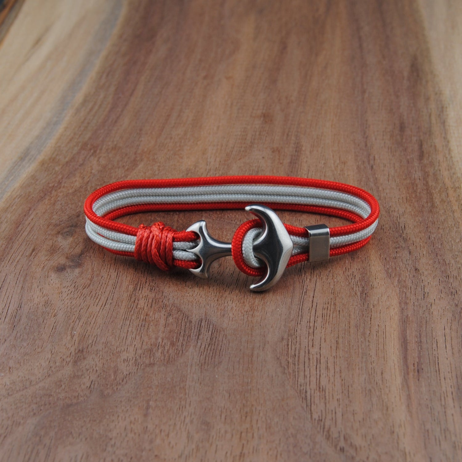 Bracelet with red and white straps and metal clasp on a wooden surface