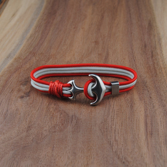 Bracelet with red and white straps and metal clasp on a wooden surface