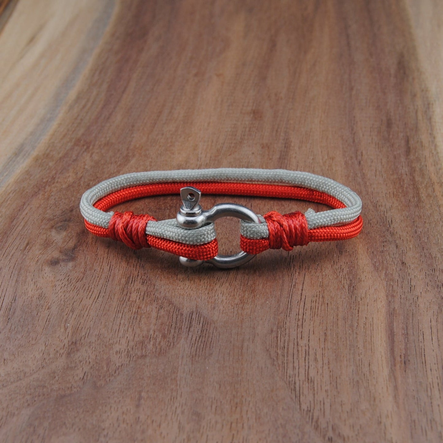 Bracelet with red cord and silver clasp on a wooden surface