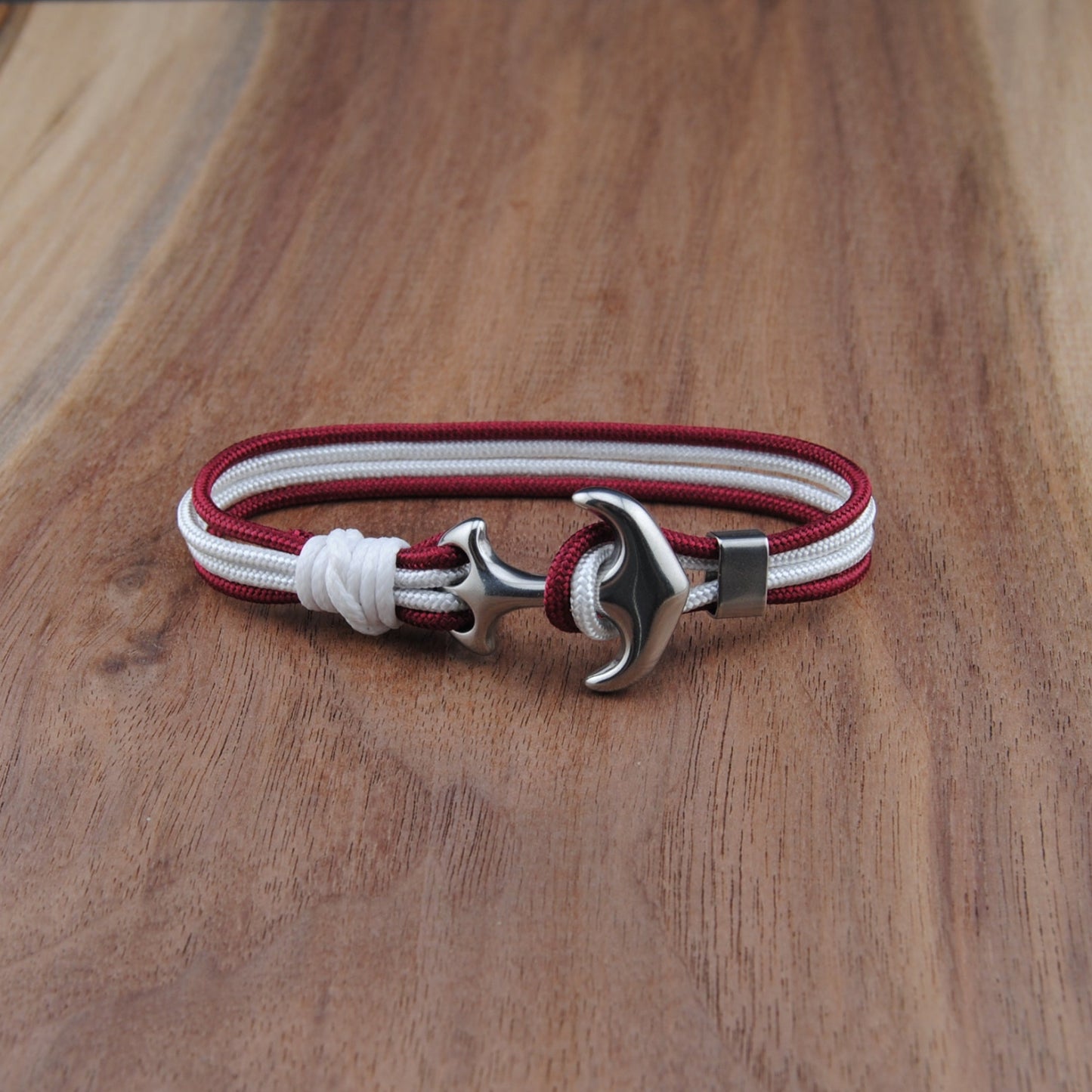 Bracelet with red and white strap and silver clasp on a wooden surface