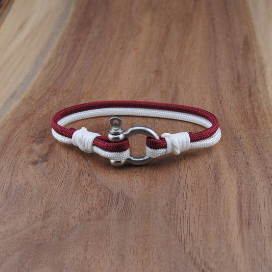 Bracelet with red and white cord on a wooden surface
