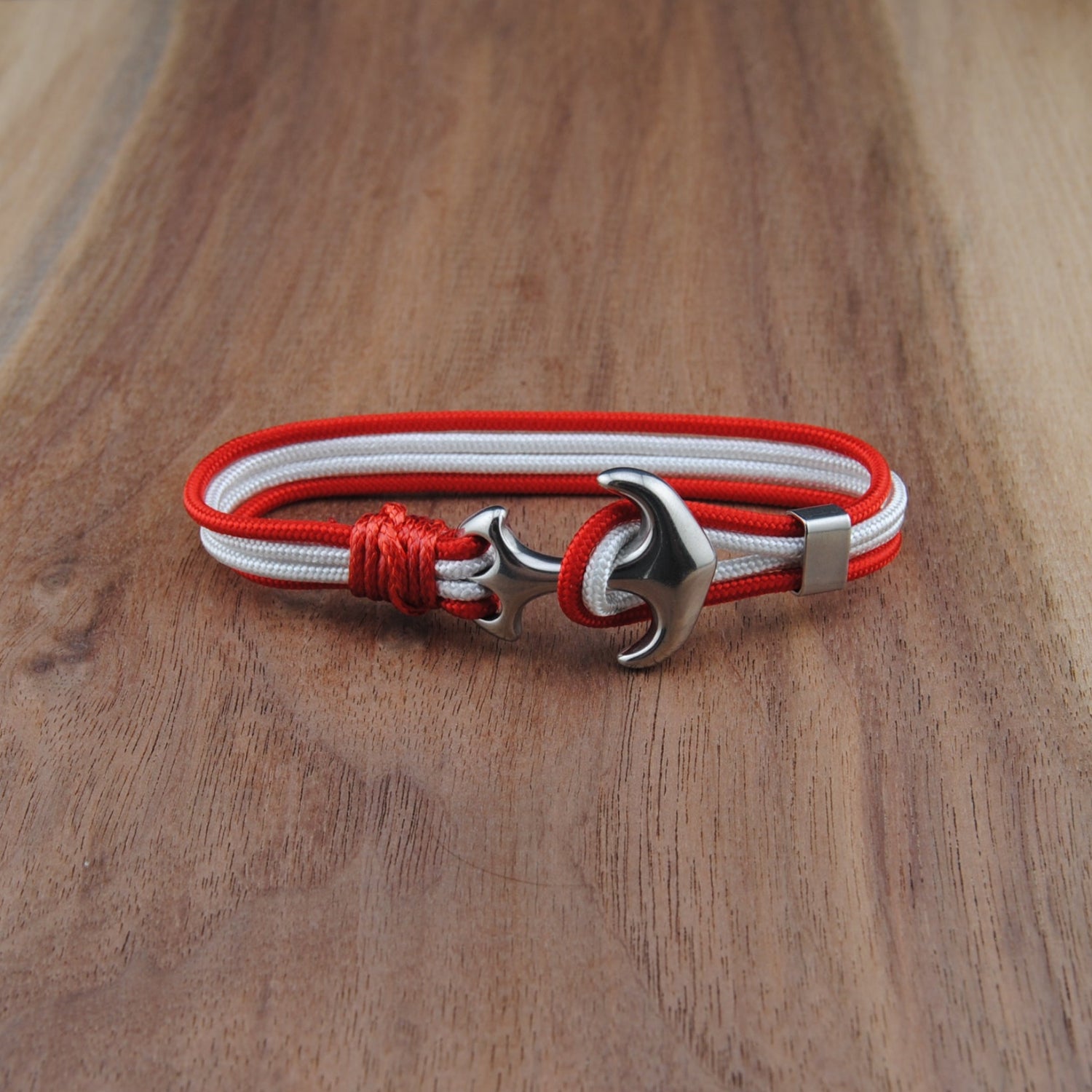 Bracelet with red and white cord and silver clasp on a wooden surface