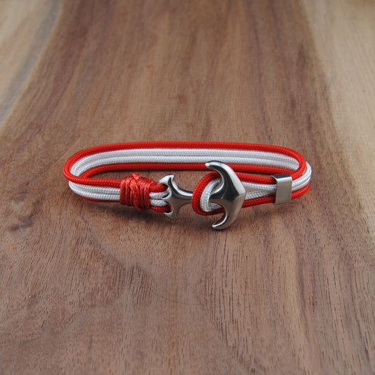 Bracelet with red and white cord and silver clasp on a wooden surface