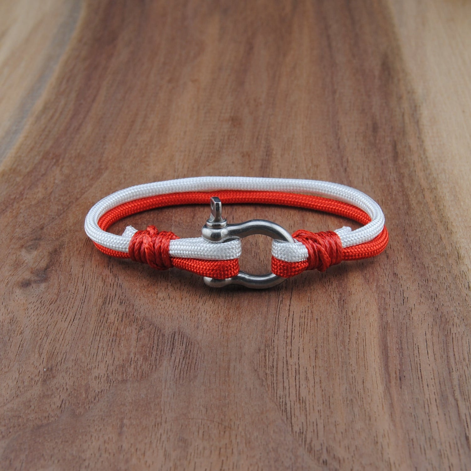 Bracelet with red and white cord on a wooden surface