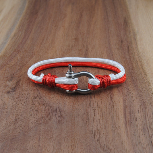 Bracelet with red and white cord on a wooden surface