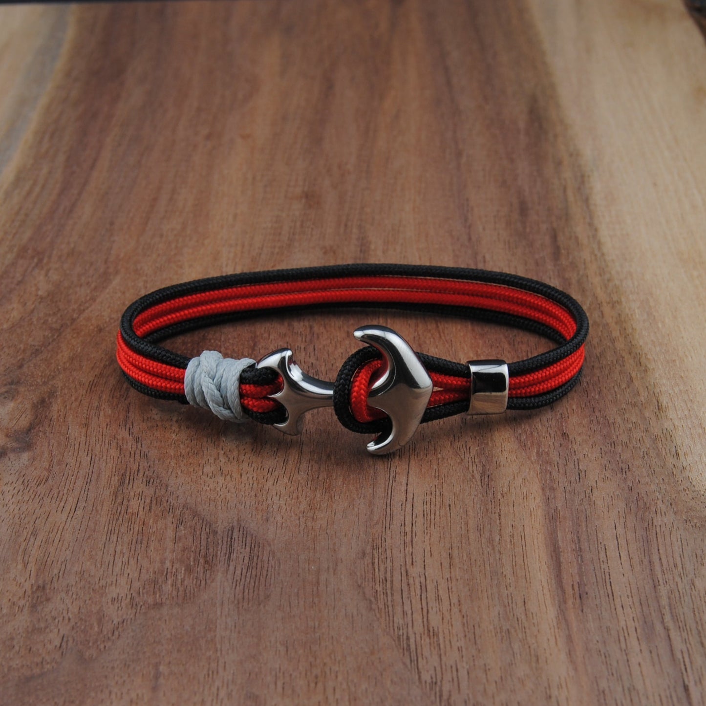 Bracelet with red and black straps on a wooden surface
