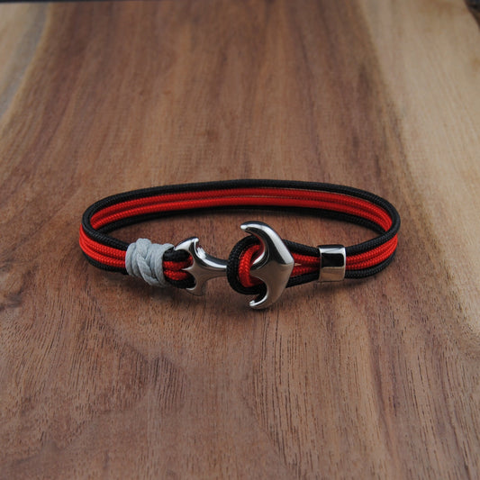 Bracelet with red and black straps on a wooden surface