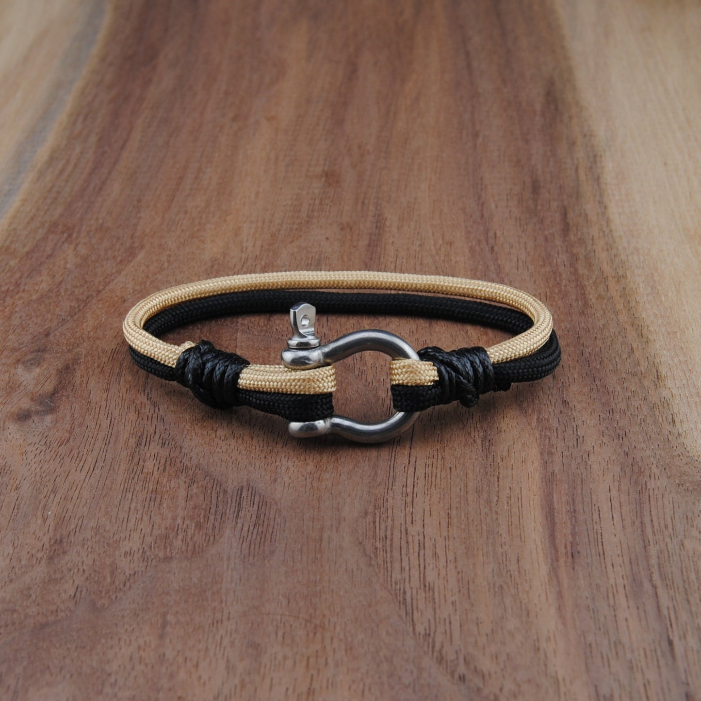 Bracelet with black and gold cord on a wooden surface