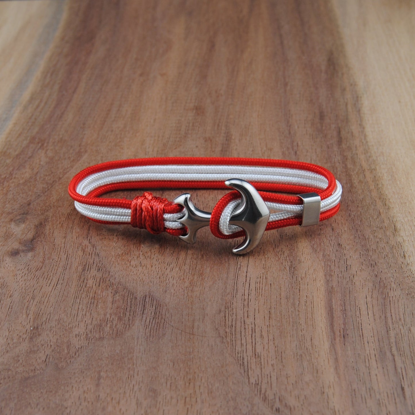 Bracelet with red and white cord and silver clasp on a wooden surface