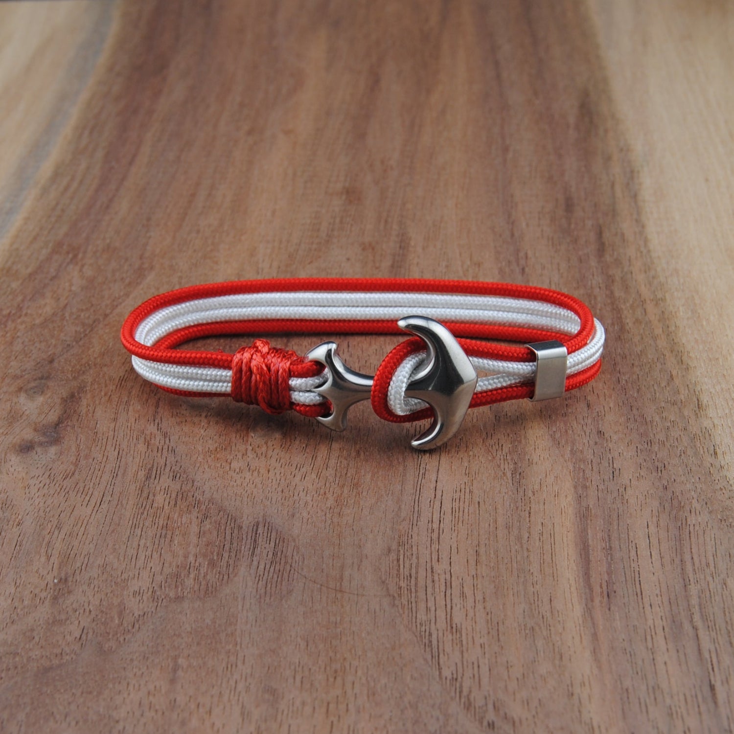 Bracelet with red and white cord and silver clasp on a wooden surface