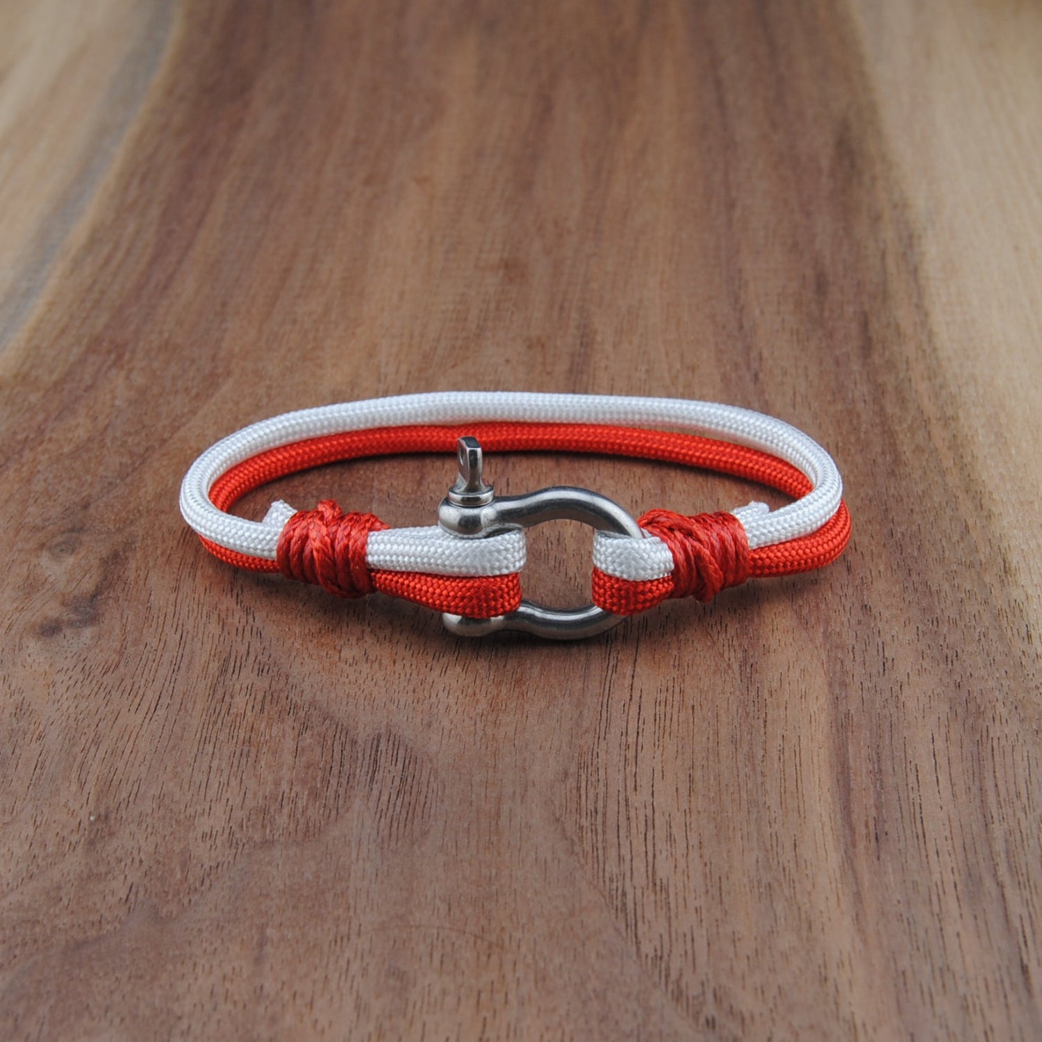 Bracelet with red and white cord on a wooden surface