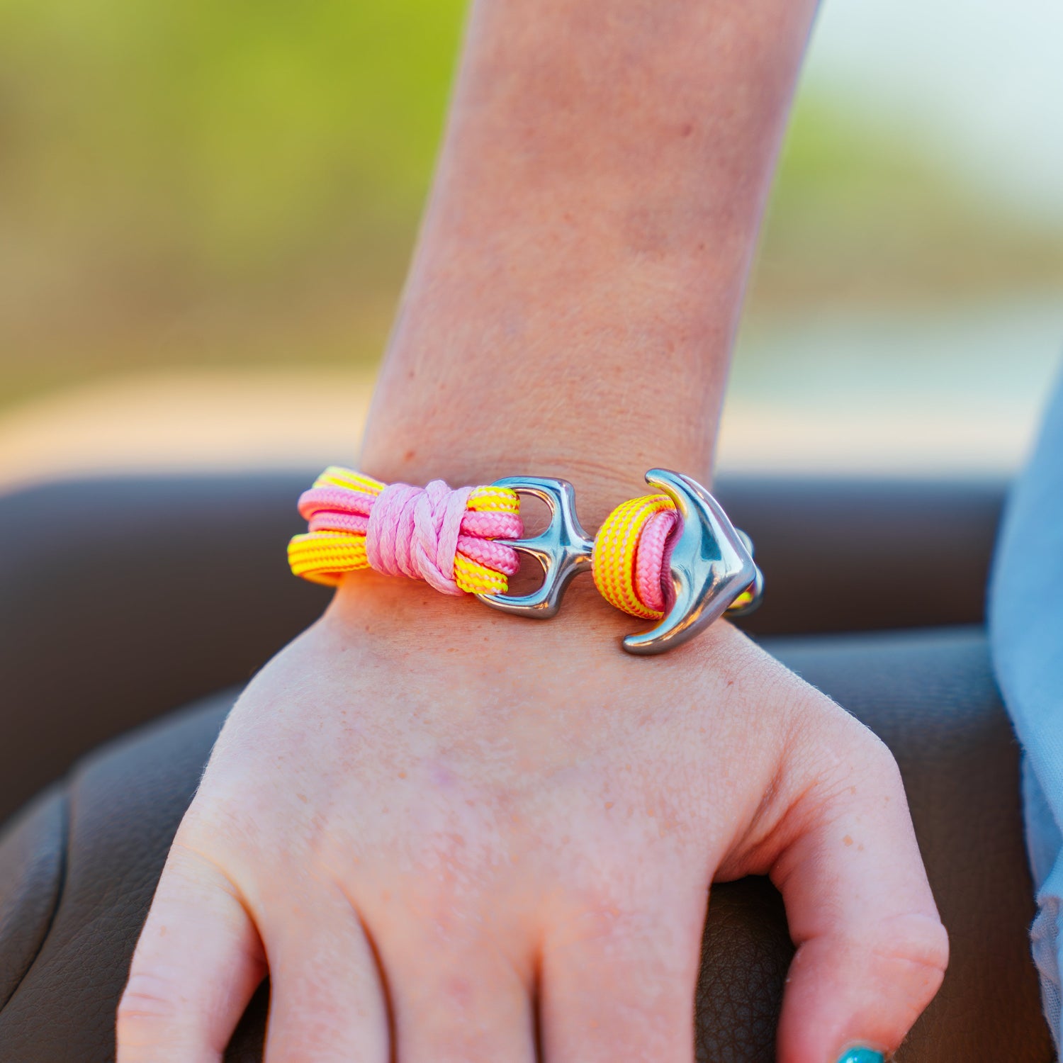 Colorful bracelet with a silver clasp on a person's wrist, sitting outdoors.