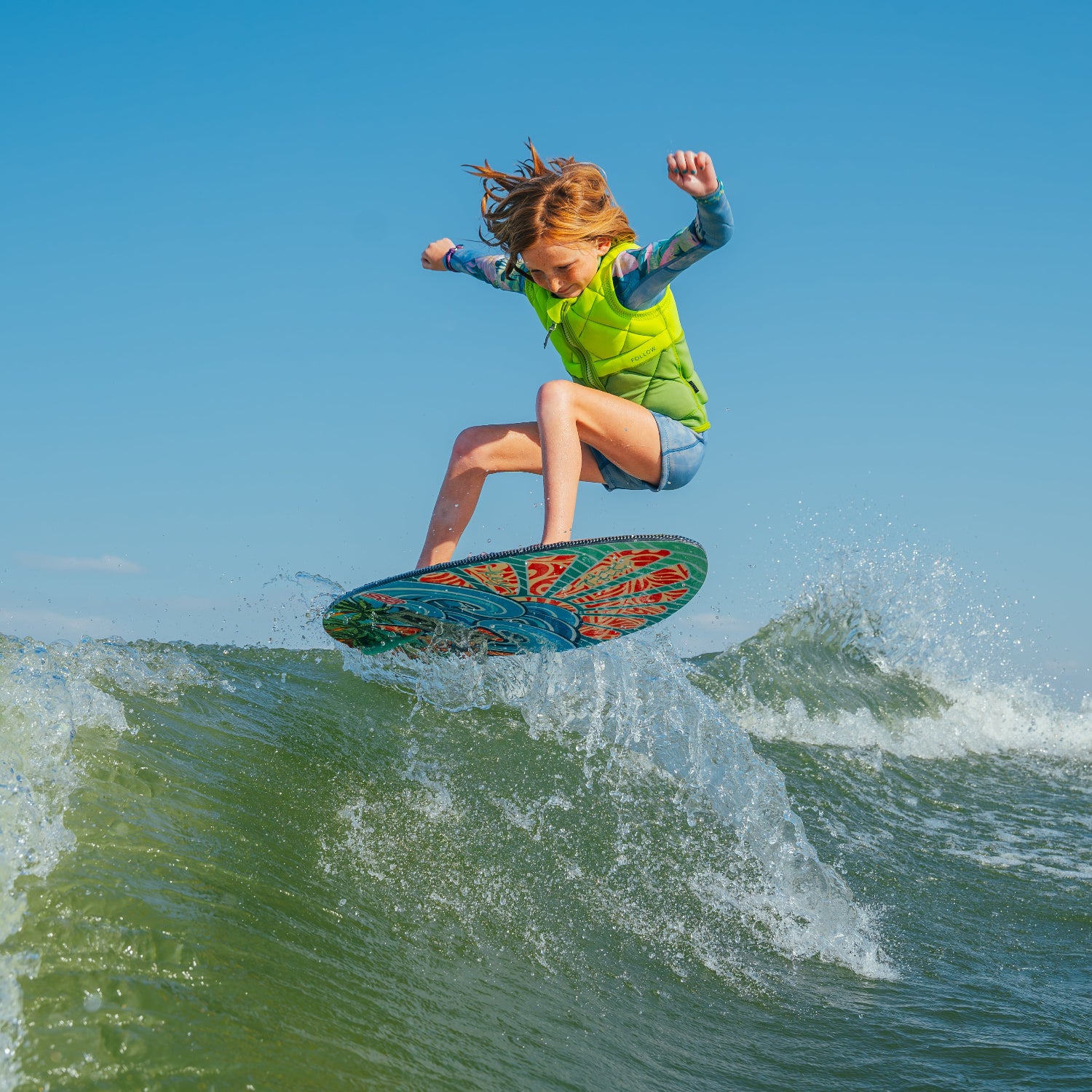 Person wake surfing on a wave with clear blue sky