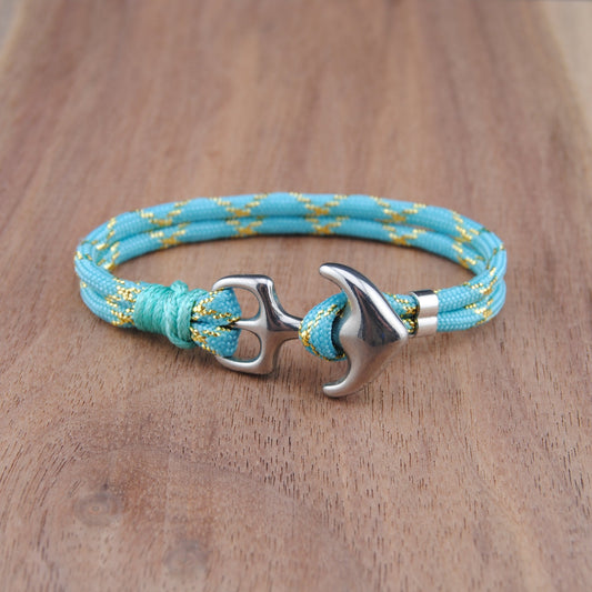 Turquoise braided bracelet with silver anchor clasp on a wooden surface