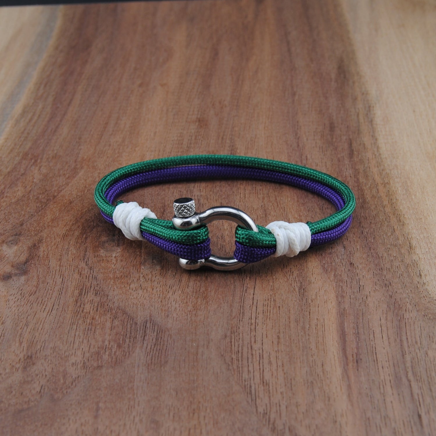 Bracelet with purple, green, and white bands on a wooden surface