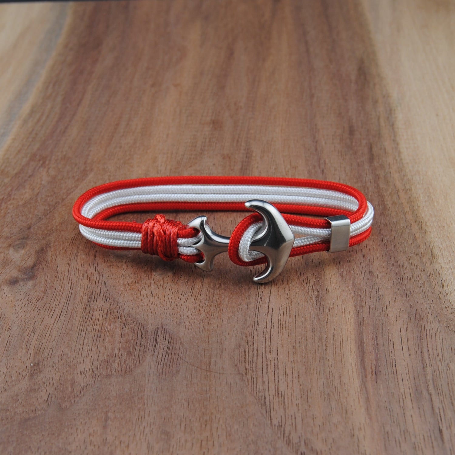 Bracelet with red and white cord and silver clasp on a wooden surface