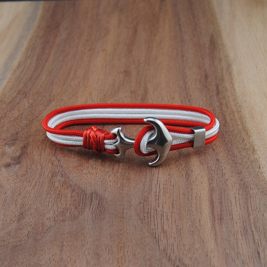 Bracelet with red and white cord and silver clasp on a wooden surface