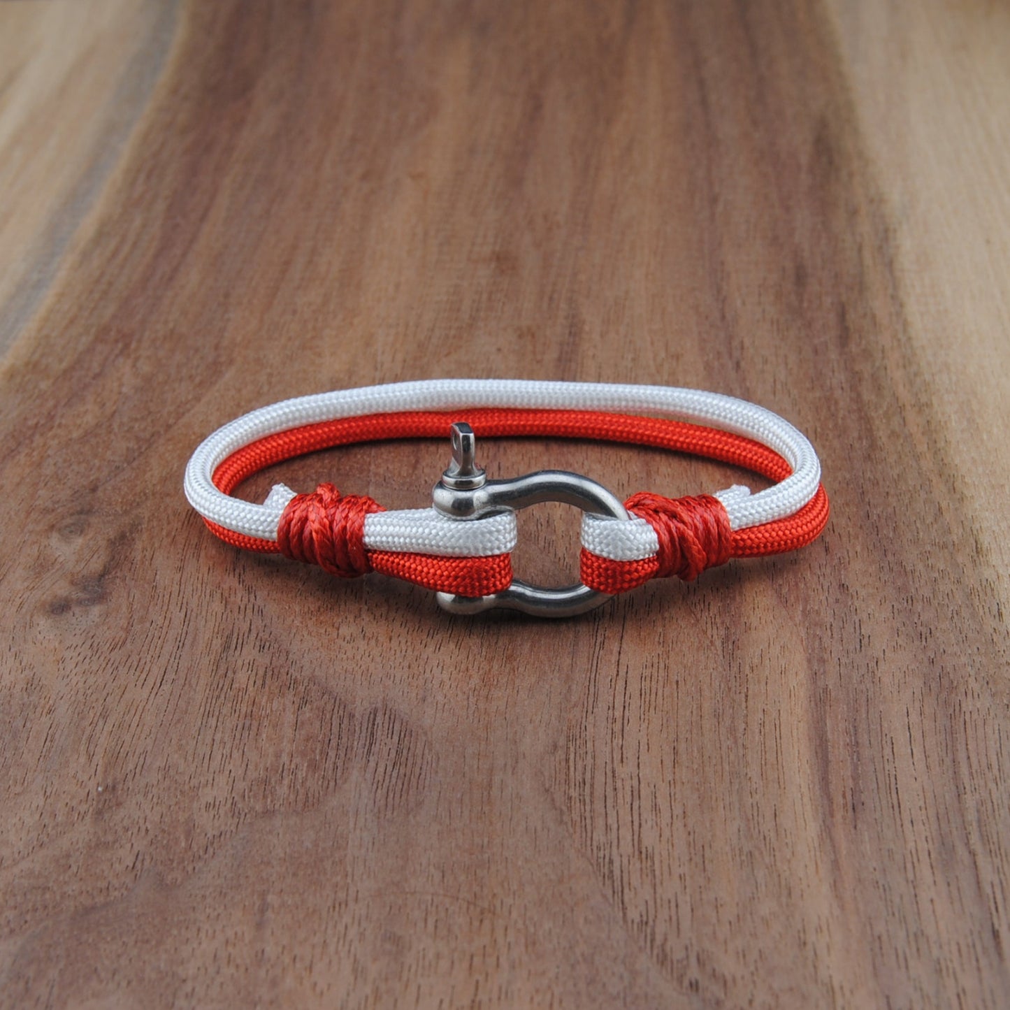 Bracelet with red and white cord on a wooden surface
