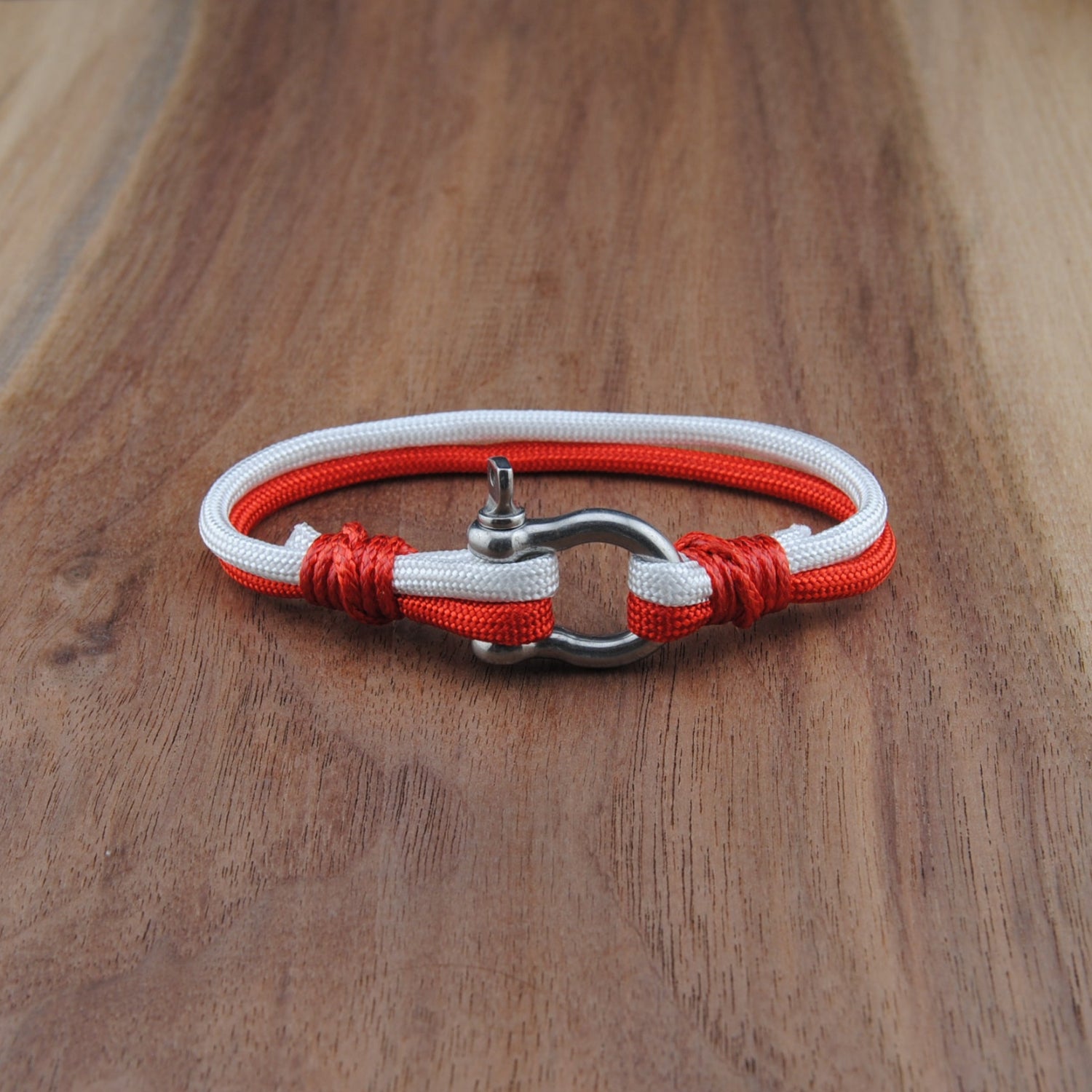 Bracelet with red and white cord on a wooden surface