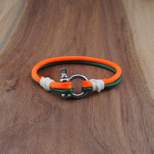 Bracelet with orange, green, and white straps on a wooden surface