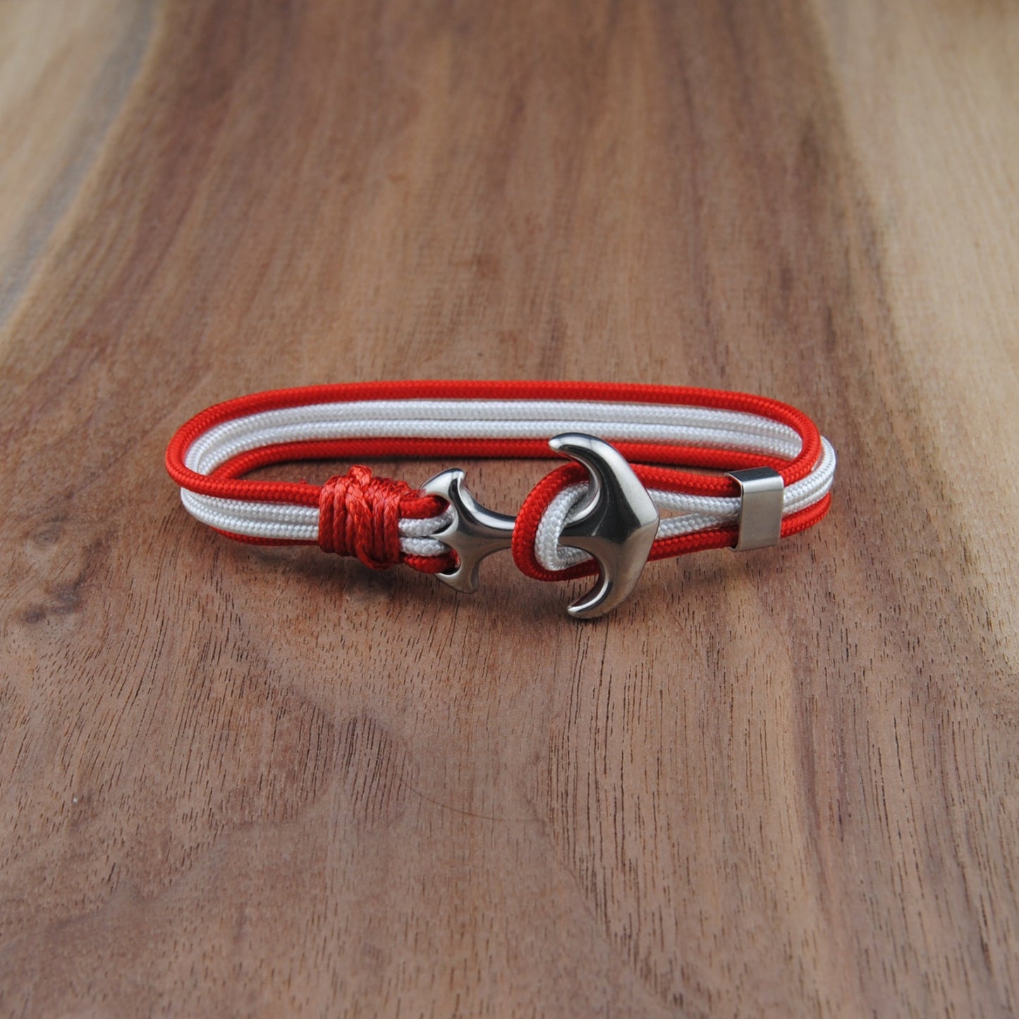 Bracelet with red and white cord and silver clasp on a wooden surface