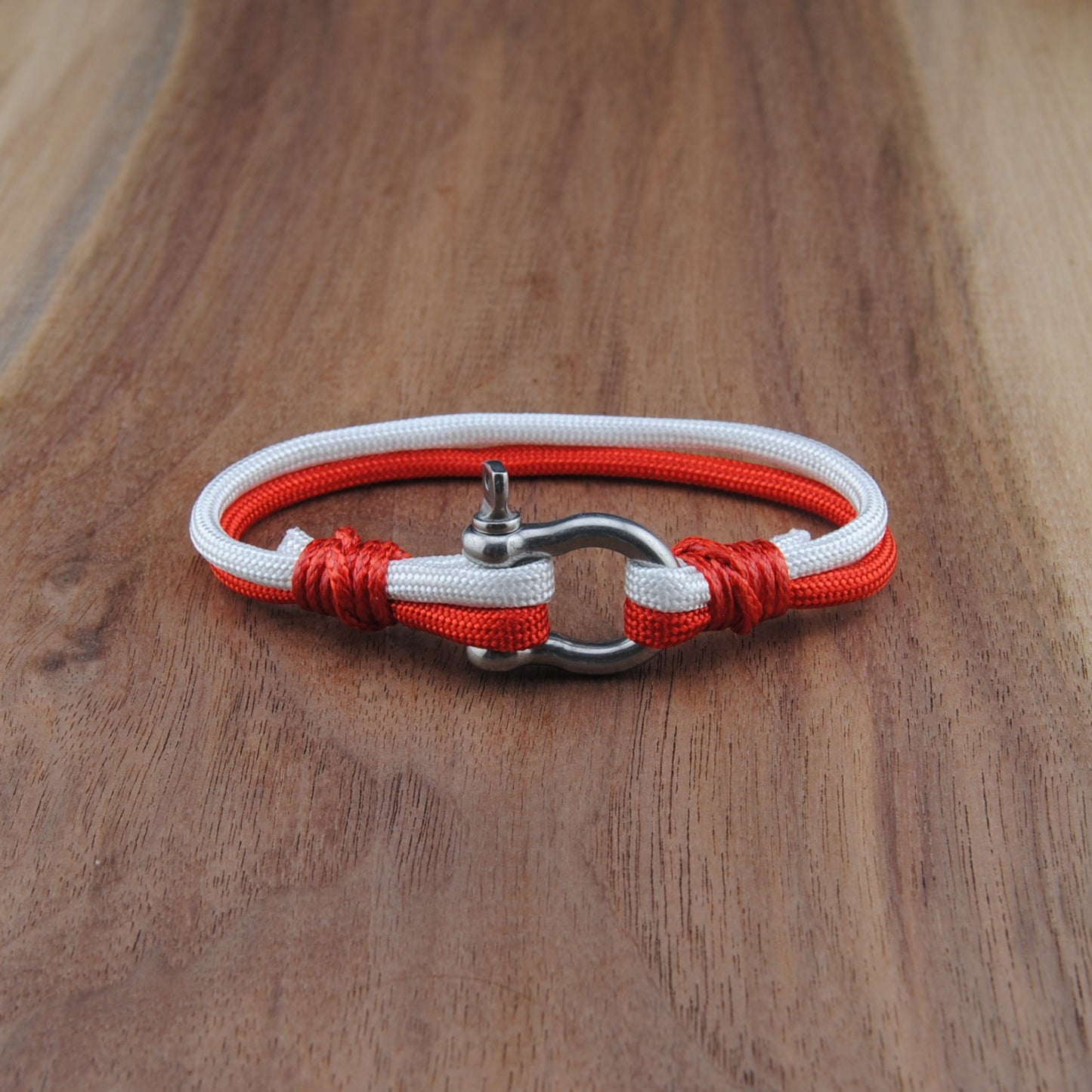 Bracelet with red and white cord on a wooden surface