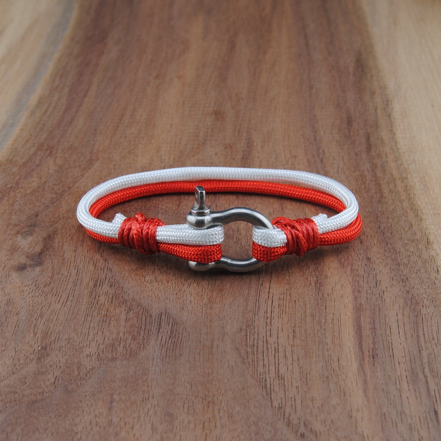 Bracelet with red and white cord on a wooden surface