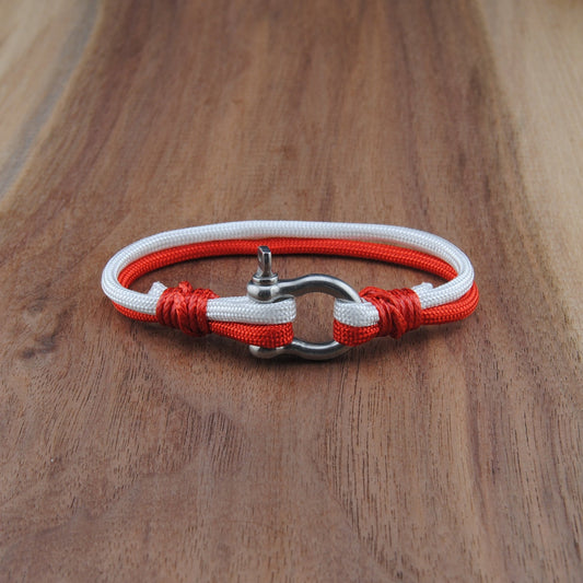 Bracelet with red and white cord on a wooden surface
