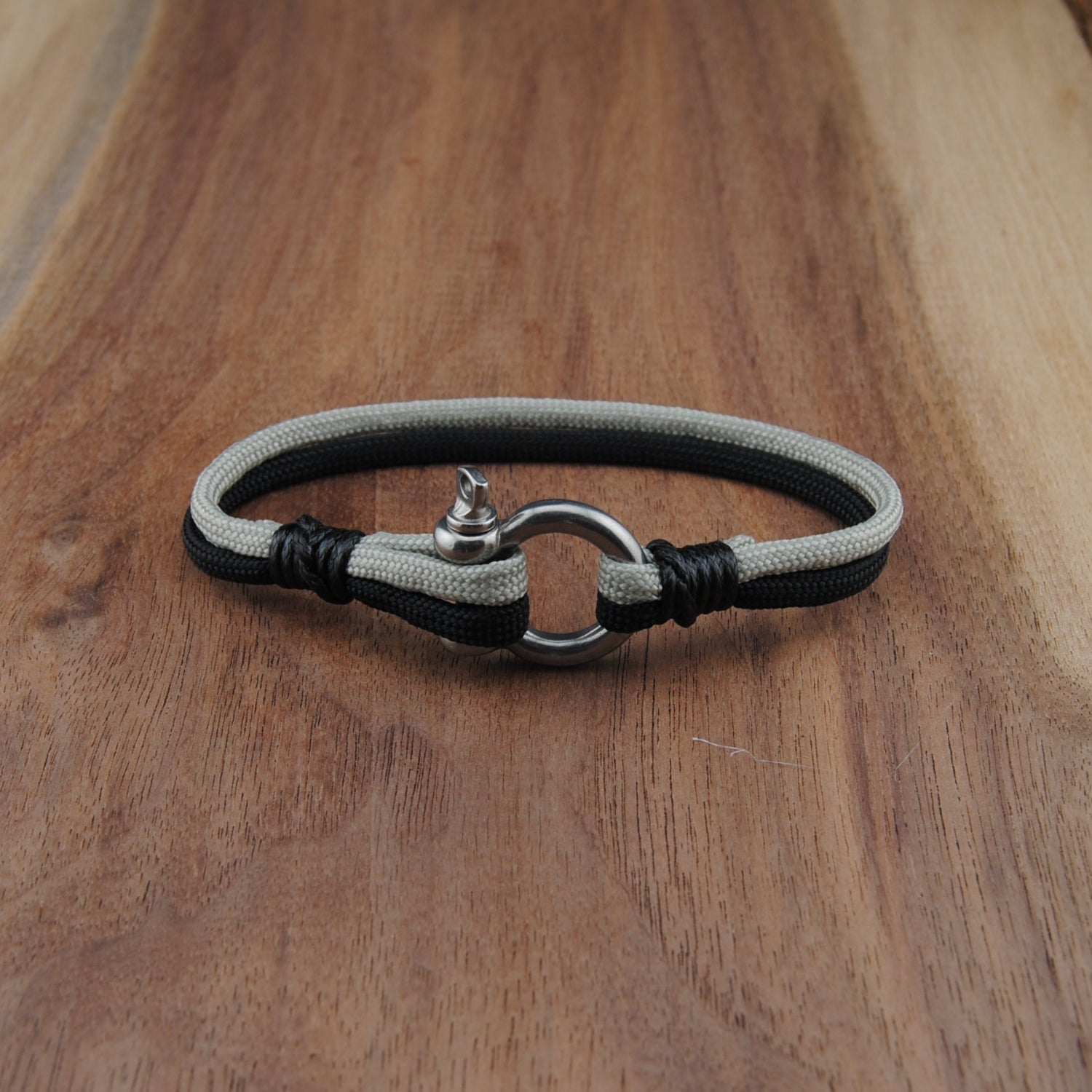 Bracelet with black and gray cord on a wooden surface