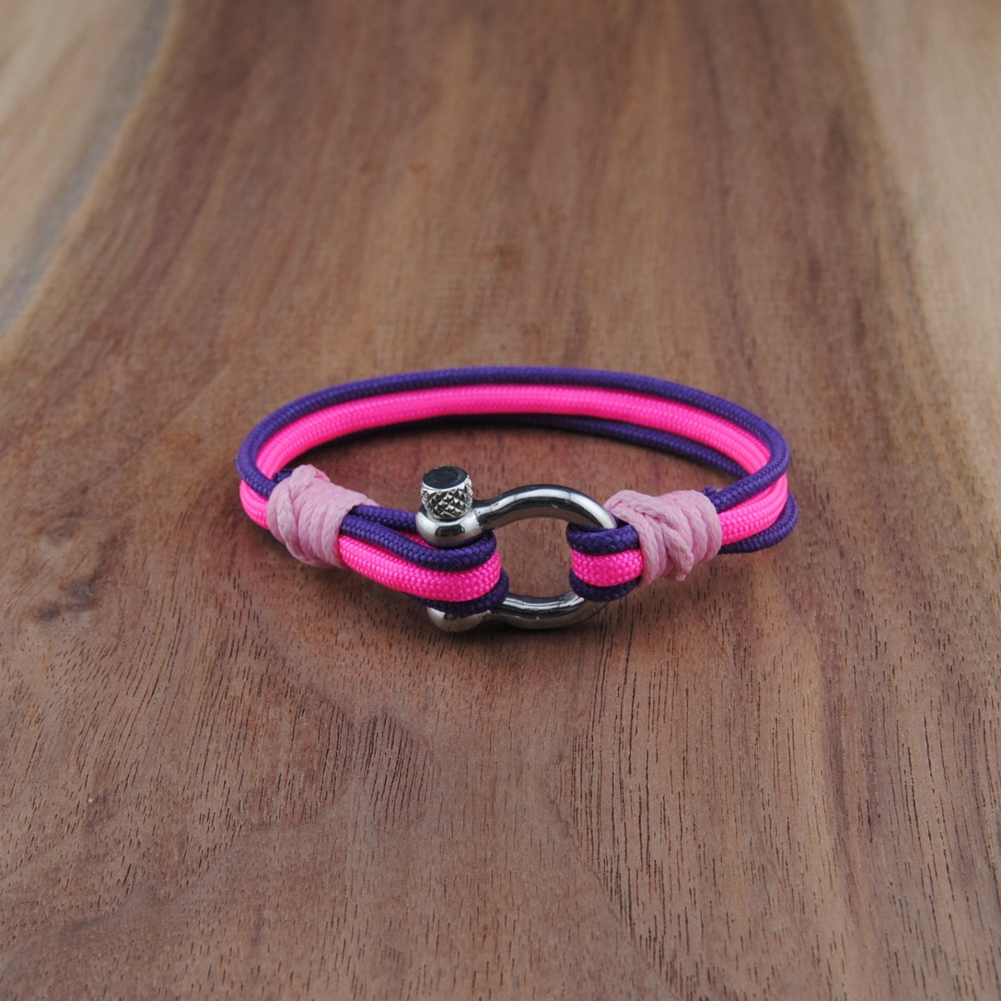 Pink and purple bracelet with a silver clasp on a wooden surface